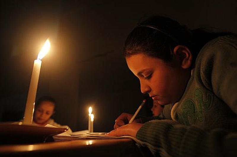 أطفال المدارس بغزة يقومون بواجباتهم المدرسية على إضاءة الشموع خلال الانقطاع المتواصل للكهرباء