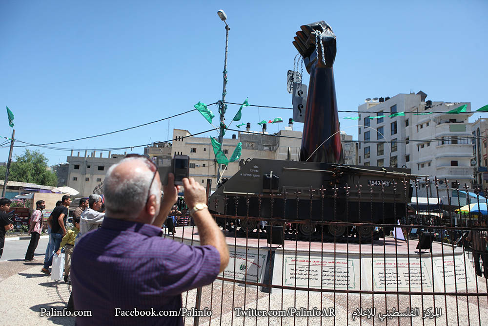 المواطنون يلتقطون صوراً تذكارية بجانب النصب التذكاري الذي شيدته كتائب القسام في ميدان فلسطين بغزة